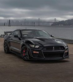 a black sports car parked in front of a body of water