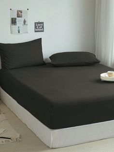 a bed sitting in a bedroom next to a window covered in black sheets and pillows