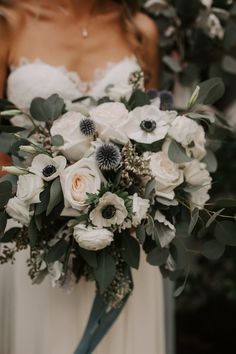 a bridal holding a bouquet of white flowers and greenery