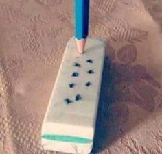 a toothbrush holder sitting on top of a bed next to a pink and blue pen