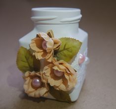 two flowers are placed on top of a white vase with green leaves and pearl beads