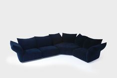 a large blue couch with black pillows on the top and bottom half, sitting in front of a white background