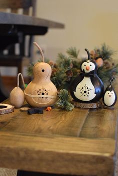 three wooden penguin figurines sitting on top of a table next to pine cones