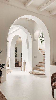 an arched doorway leads to a living room with white walls and carpeted flooring