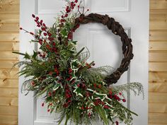 a wreath with red berries and greenery hangs on the front door's white door