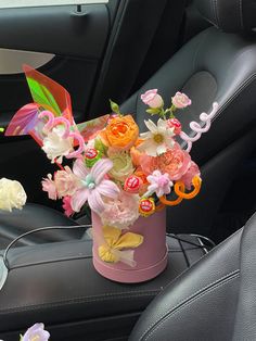 a vase filled with colorful flowers sitting on top of a car seat next to a steering wheel