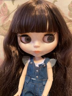 a doll with long brown hair wearing overalls