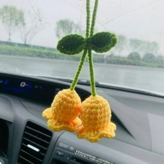 two crocheted baby booties hanging from the dashboard of a car