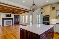 an empty kitchen and living room with wood floors, white cabinets, and a large center island