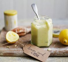 a jar of lemon curd sitting on top of a cutting board next to two lemons