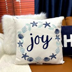 a pillow with the word joy on it sitting on a chair next to a pillow