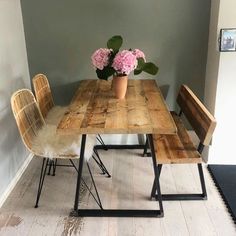 a wooden table with two chairs and a vase filled with flowers on top of it