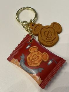 a cookie shaped keychain with a mickey mouse design on it's side