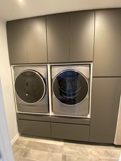 a washer and dryer in a room with gray cabinets on the wall behind them