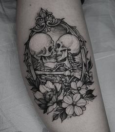 a couple of skulls sitting on top of each other in a circle with flowers around them