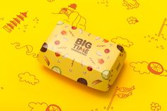 a yellow box sitting on top of a yellow surface with cartoon drawings and clouds around it