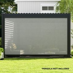 a large screen in the middle of a yard with grass and trees behind it, next to a white house