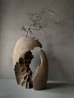 a sculpture made out of stone with a tree growing from it's head in the center