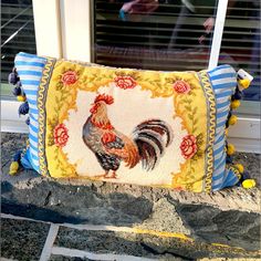 a decorative pillow with a rooster on it sitting in front of a window sill