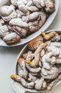 two white bowls filled with powdered sugar covered pastries