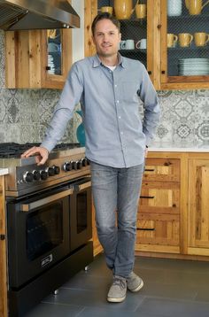 a man standing next to an oven in a kitchen