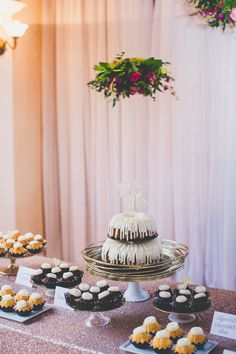 a table topped with cakes and cupcakes covered in frosting on top of a table