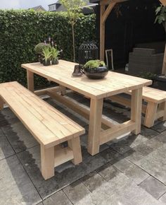 a wooden table and bench sitting in the middle of a patio with potted plants