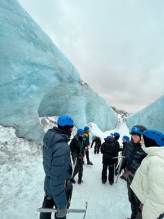 a group of people standing next to each other in front of an ice cave with snow on the ground