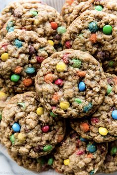 cookies with m & m's and chocolate chips on top are piled up in a bowl