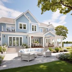 a large blue house with lots of windows and white furniture in front of the house