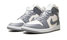 The Women’s Air Jordan 1 Mid “Stealth” is a women’s version of the popular sneaker in a versatile colorway.  The “Stealth” features a two-tone color block with Sail-colored leather on its perforated toe, mid-panel, and collar.  Both the overlay panels and Swoosh are designed in Stealth (grey) leather.  A Sail “Wings” logo appears on the collar while grey Jumpan and “Air” branding can be found on the tongue tag.  The white nylon tongue is contrasted with grey laces.  Underfoot, a white midsole and grey rubber outsole complete the look. Air Jordan 1 Mid Stealth, Jordan 1 Mid Stealth, Air Jordan 1 Mid Grey, Sneakers Box, Kobe Shoes, Nike Swoosh Logo, Nike Air Jordan 1 Mid, Streetwear Accessories, Womens Air Jordans