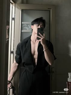 a shirtless man taking a selfie in front of a mirror with his cell phone