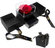 two black boxes with a single red rose in it and ribbon tied around the box