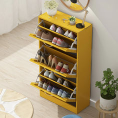 a yellow shoe rack with several pairs of shoes on it next to a potted plant