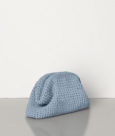 a crocheted blue purse sitting on top of a gray table next to a white wall