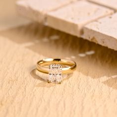 an engagement ring sitting on top of a piece of paper next to a stone block