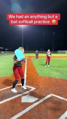 a woman holding a bat standing on top of a baseball field with other people in the background