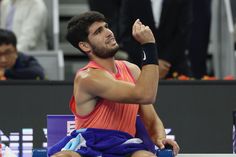 a male tennis player sitting on the court and raising his fist in celebration with people watching