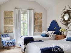 two beds in a bedroom with blue and white decor