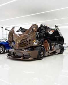 two cars are parked side by side in a garage, one is brown and the other is blue