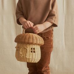 a little boy holding a wicker basket with a house on it's side