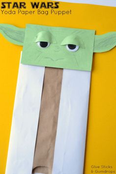 an origami yoda paper bag puppet with eyes and nose on yellow background