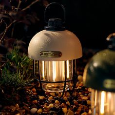 a light that is sitting on some rocks and gravel in the dark with it's lights turned on