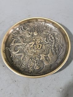 a silver and gold plate sitting on top of a white counter next to a wall