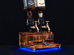 two bottles of alcohol sitting on top of a wooden box with blue light underneath it