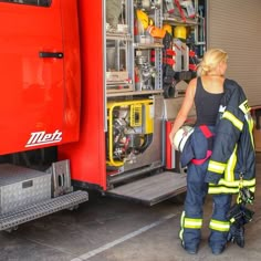 a woman in firefighter gear standing next to a fire truck with its door open