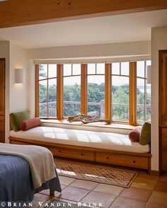 two beds in a room with wooden floors and windows overlooking the trees outside, one has a blue blanket on it