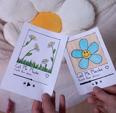 two children's hands holding up cards with pictures of flowers and bees on them