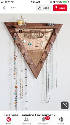 a wooden triangle with many necklaces hanging from it's sides on a wall