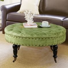 a green ottoman sits in the middle of a living room with a coffee table on it